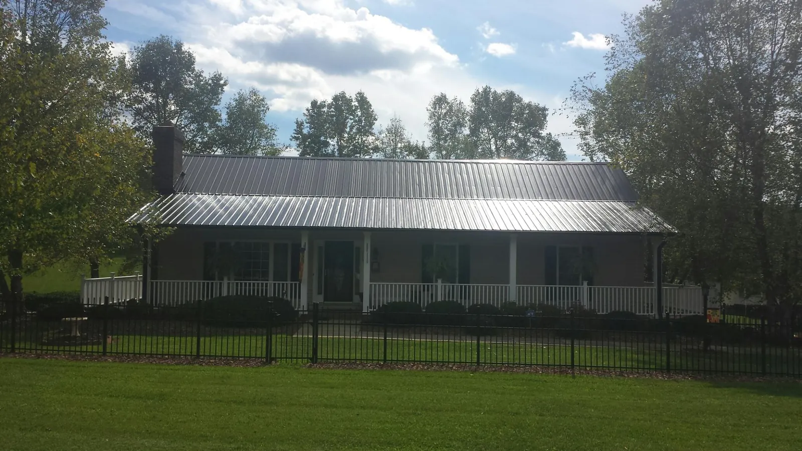 Gray metal roof on a brick ranch with a full width front porch — Gutter Guard Installation work by our crew in Lawtey