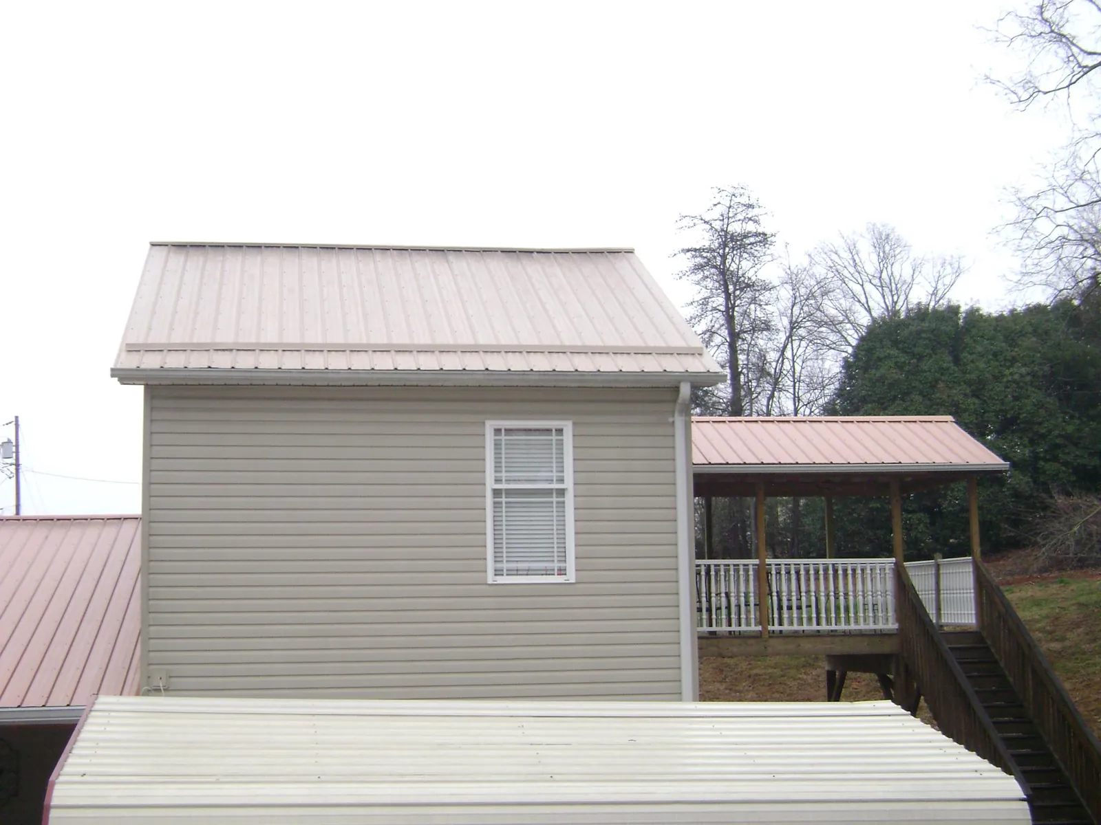 Tan metal roofs on a two story addition and attached porch, from a Roof Replacement job in Lawtey